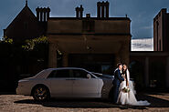 couple share a moment in front of a rolls Royce