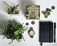 Varios objetos: monedas, una planta, un libro, un ambientador de varillas, un reloj, un bolígrafo...