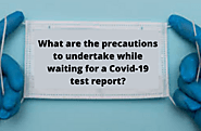 What are the precautions to undertake while waiting for a Covid-19 test report?