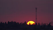 The sun setting behind cell tower