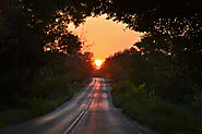 The sun sets at the end of the road
