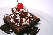 Fudge Brownie with ice cream, chocolate syrup, and a cherry on top.