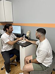 A podiatrist at Inertia Health Group Clinic conducting a detailed examination on a patient, focusing on foot and ankl...