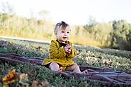 Baby earing yellow crochet long sleeve dress sitting on ~Sanjeev Nanda